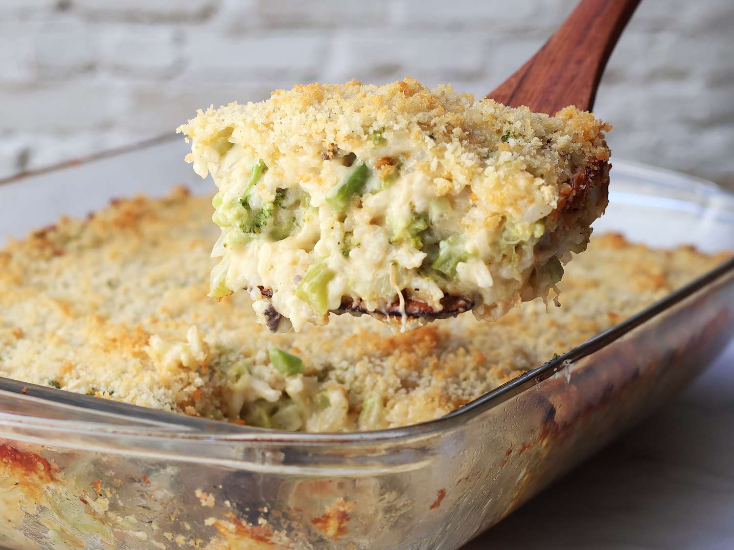 A broccoli rice casserole in a rectangular baking dish just out of the oven, with melted cheese bubbling and lightly browned spots across the top