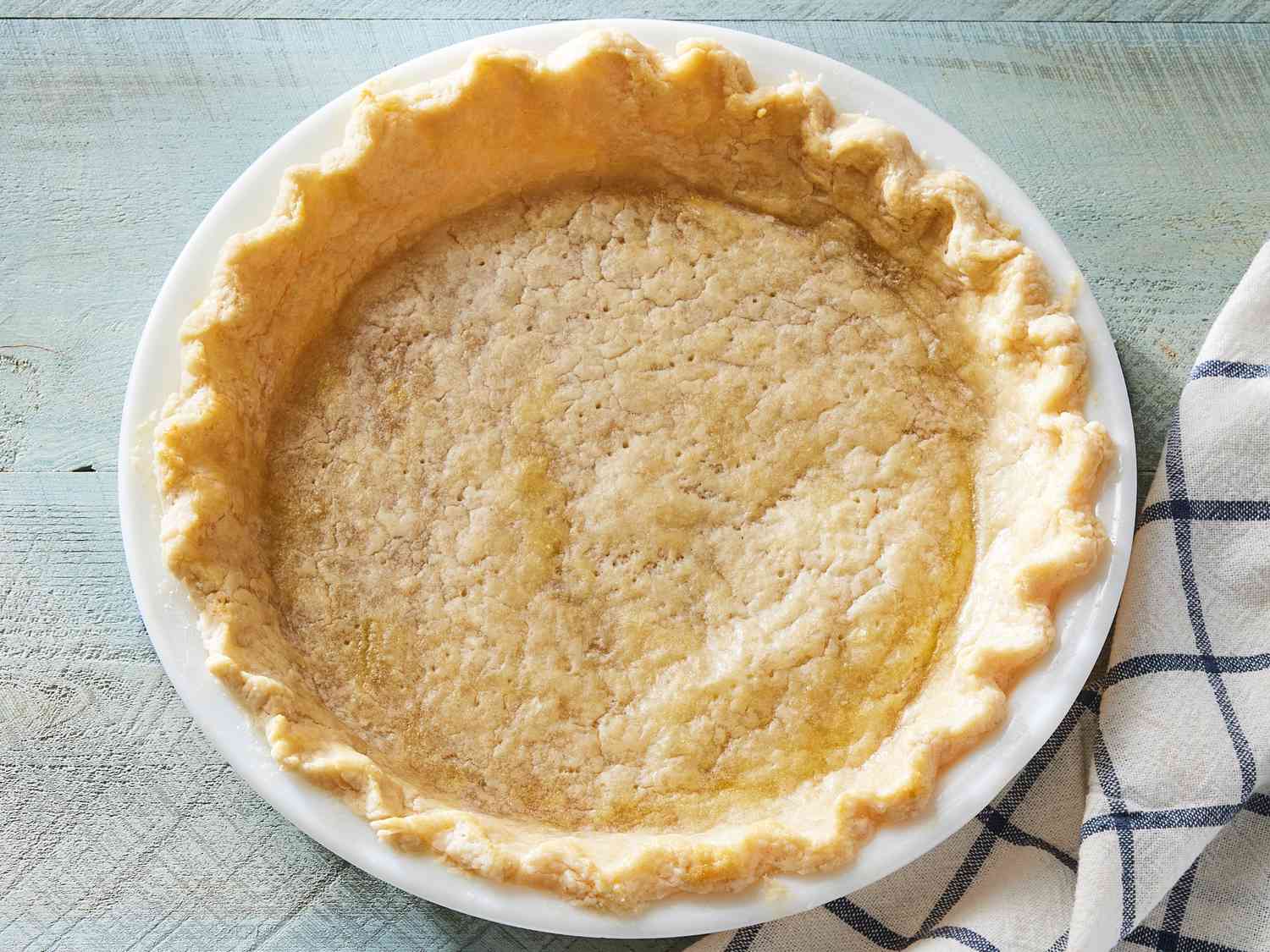 A close view of pie dough pressed into a disk with visible pea-size butter pieces and a slightly shaggy surface
