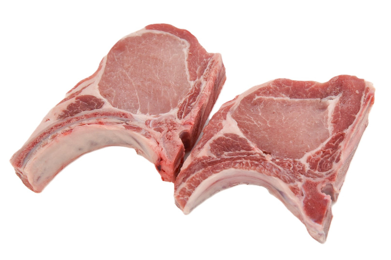 A raw bone-in rib pork chop on butcher paper showing visible marbling and a thick cut, photographed in natural kitchen light