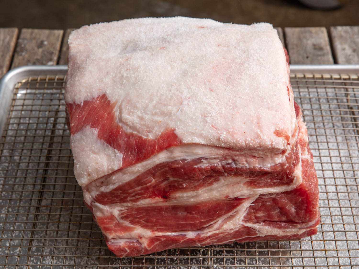 A raw pork shoulder roast on a cutting board with visible marbling and a small fat cap