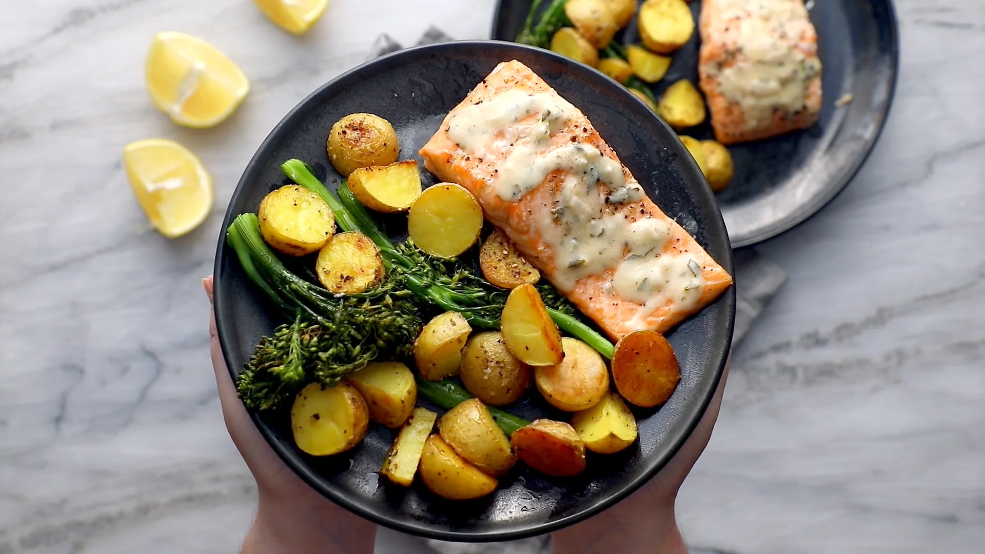 A roasted salmon fillet on a white plate with a spoonful of savory lemon curd melting over the top and scattered chopped chives
