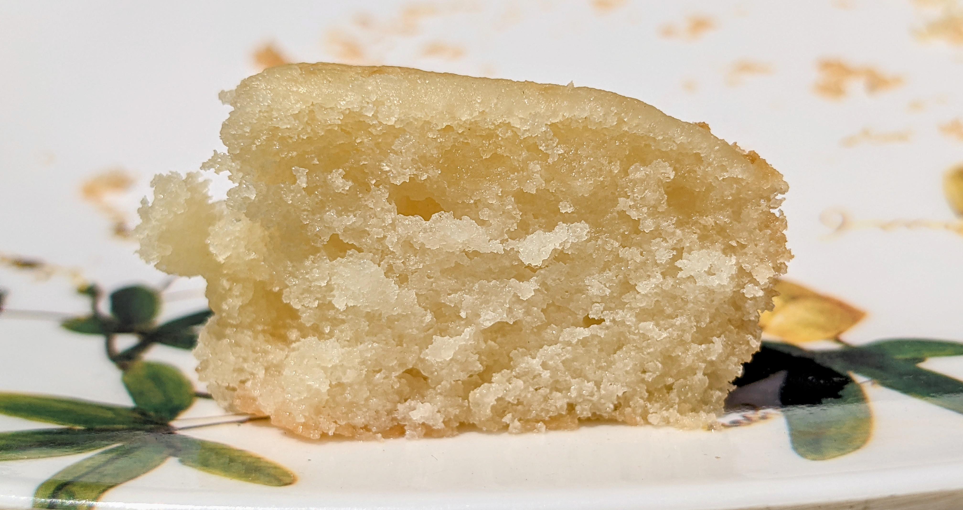 A single slice of vanilla cake on a plate showing a tight, heavy crumb with a slightly gummy center, natural kitchen light