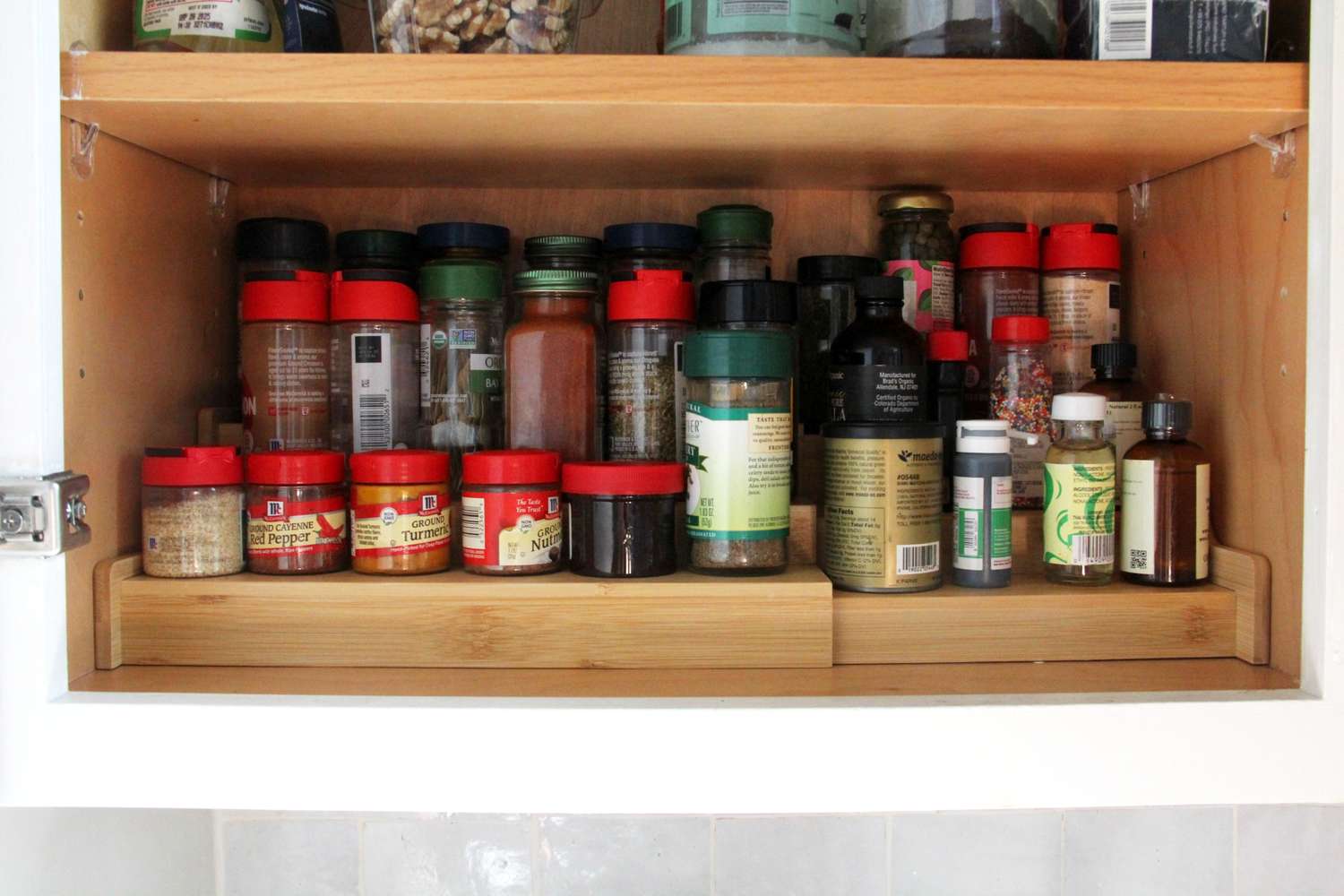A tidy pantry shelf with small glass jars of spices, including a jar of homemade taco seasoning with a metal lid, lit by warm natural kitchen light