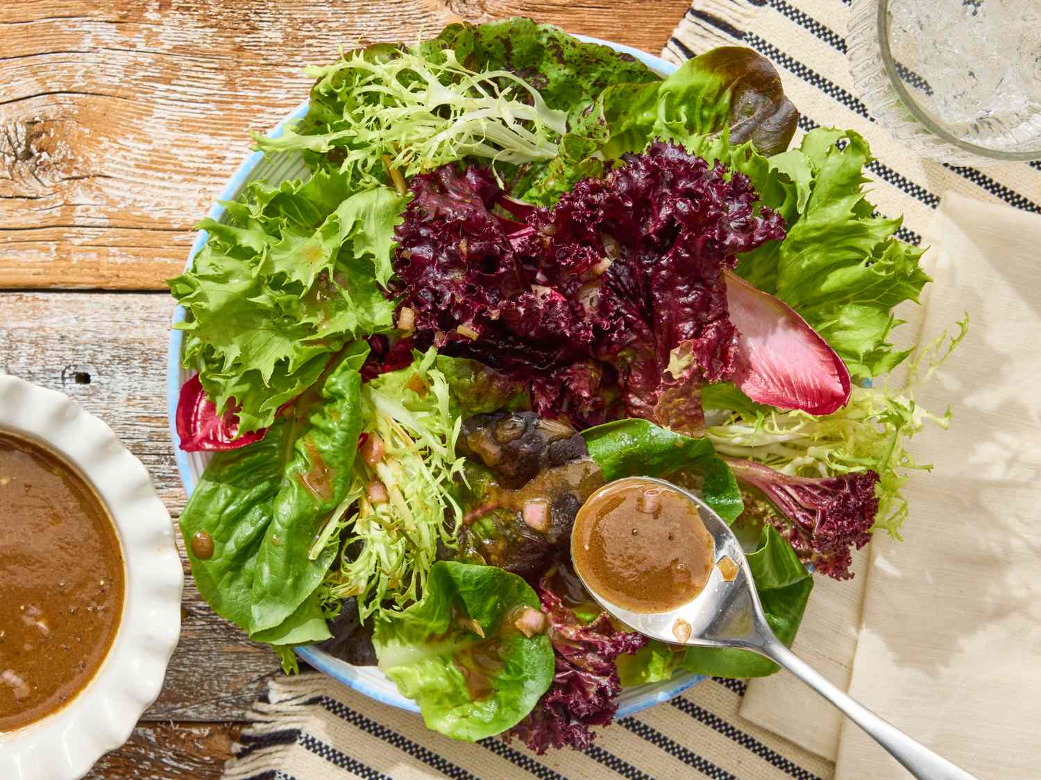 Balsamic vinaigrette poured in a thin stream over mixed greens with cherry tomatoes and shaved Parmesan