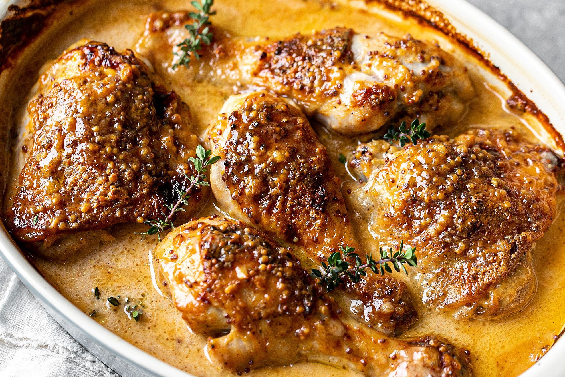 Honey mustard chicken baking in a glass dish in the oven, sauce bubbling around the edges and beginning to caramelize