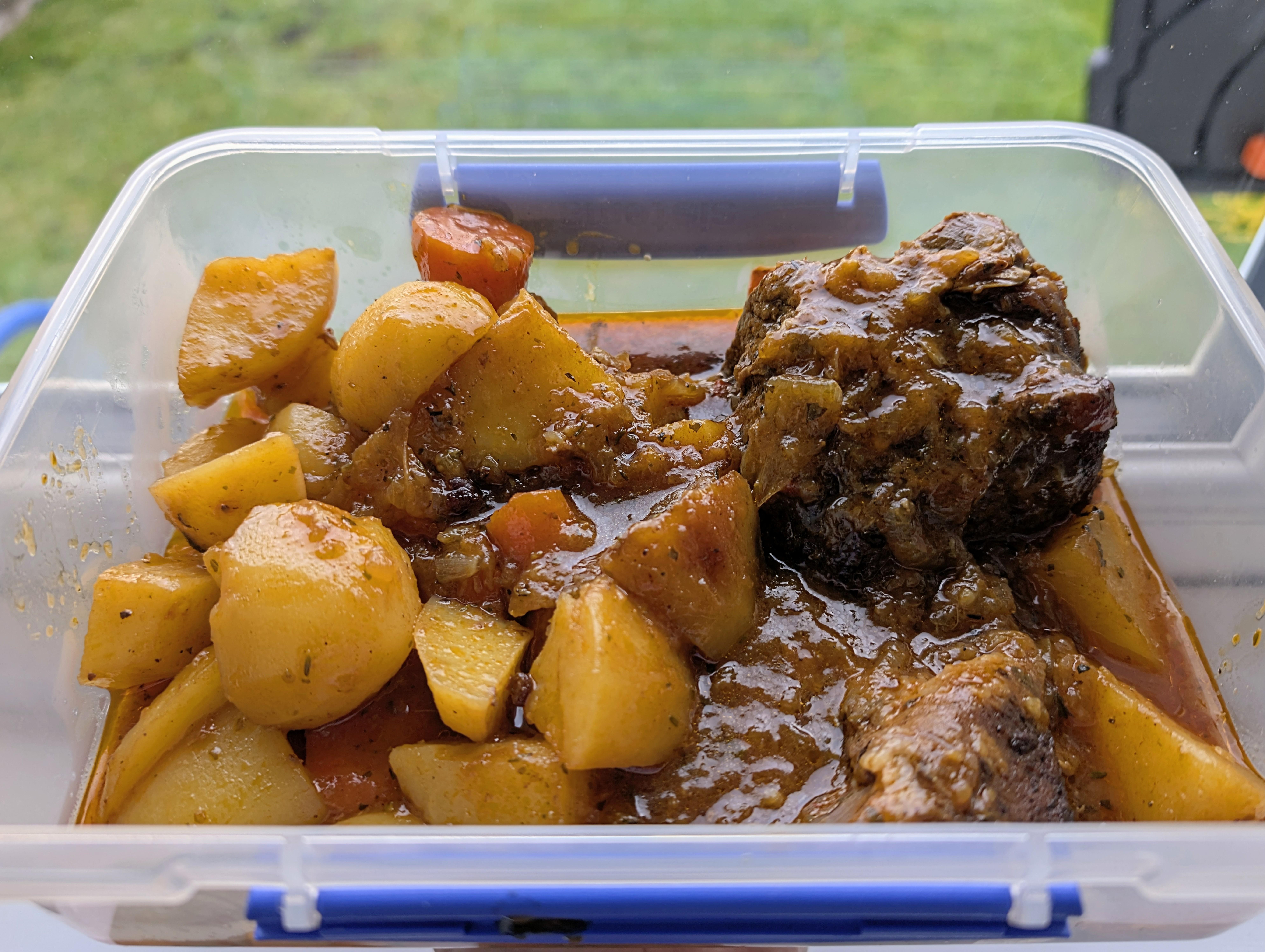 Leftover beef stew stored in a clear glass container with a tight-fitting lid on a kitchen counter